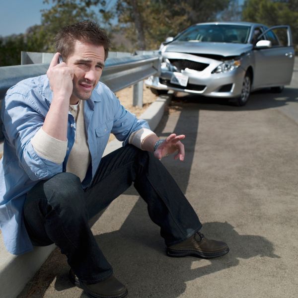 Man on the phone in front of car wreck