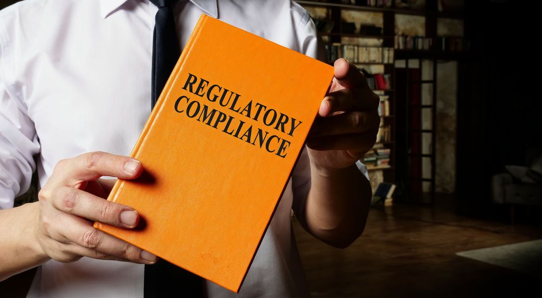 man holding book that says regulatory compliance