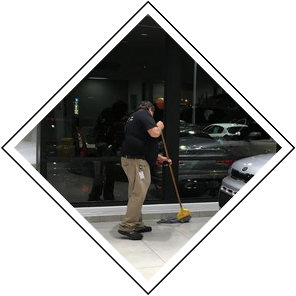 man mopping the floor at a car dealership