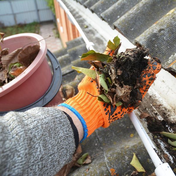 Person cleaning their gutters of leaves and other debris.