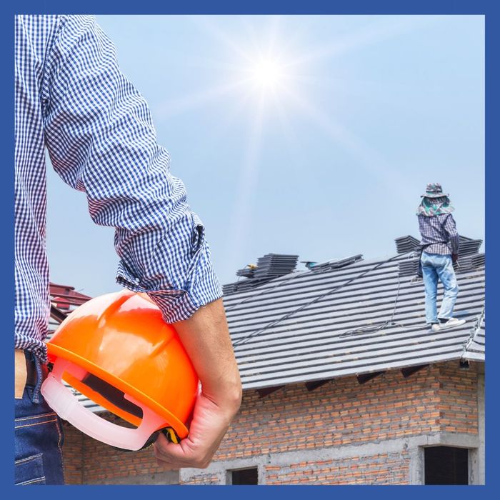 Roofer looking at home with helmet in hand
