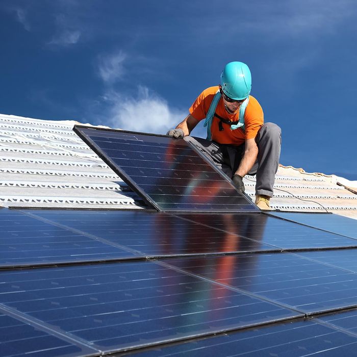 man installing solar panels on a roof