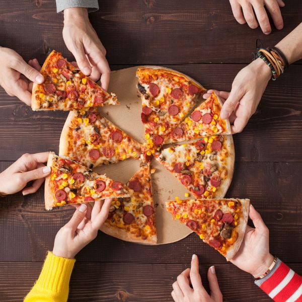 people grabbing slices of pizza