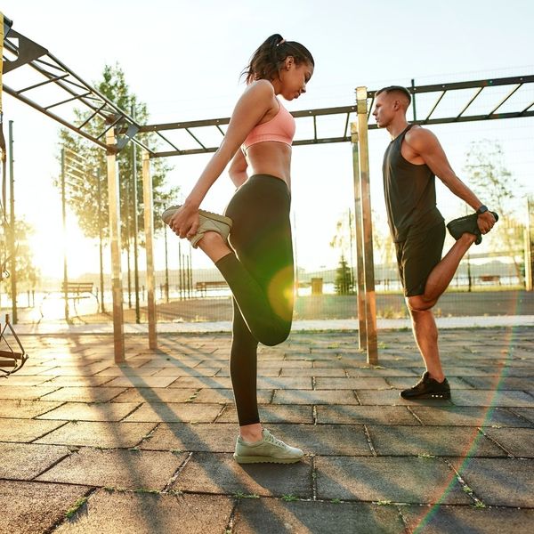 a man and a woman stretching their legs outside