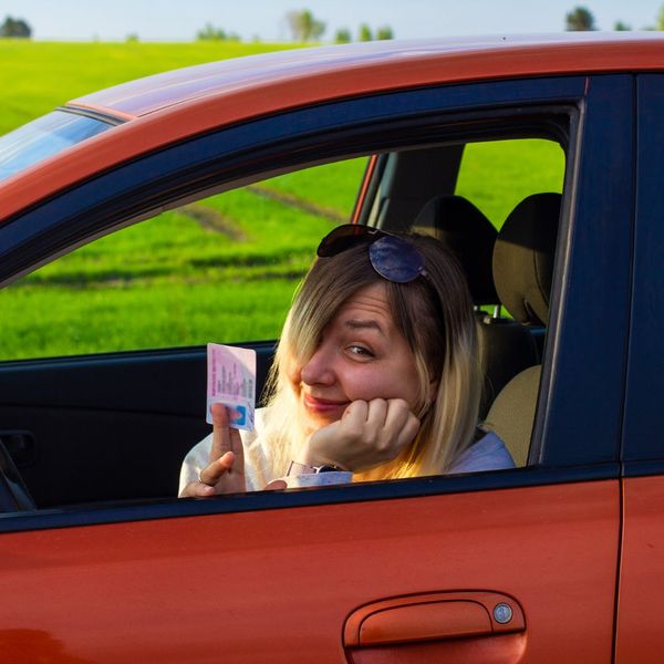 girl holding up her drivers license