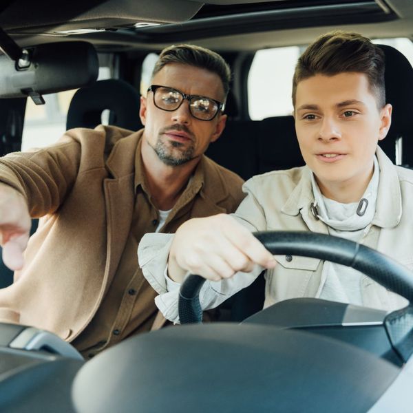 man teaches teenage boy to drive