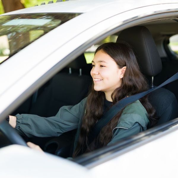 a teenage girl wears her seatbelt in a car