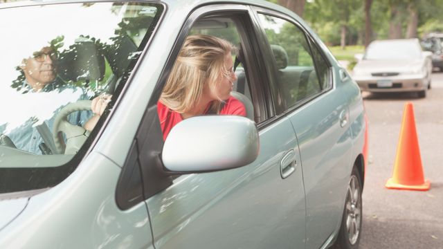 Girl learning to drive. Backing up her car