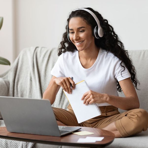 Woman smiling looking at a laptop and wearing headphones
