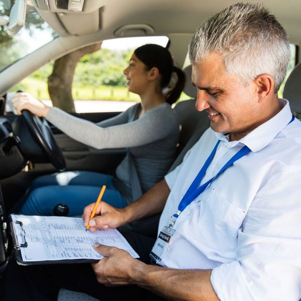 driving instructor filling out checklist in a car with student