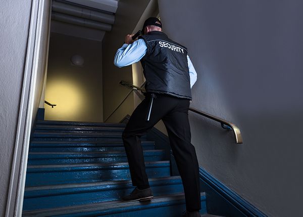 a security guard walking up dark steps with a flashlight