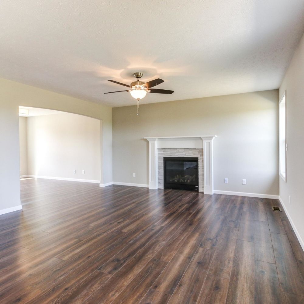 Remodeled living room featuring new dark wood-style flooring and a white fireplace mantel.