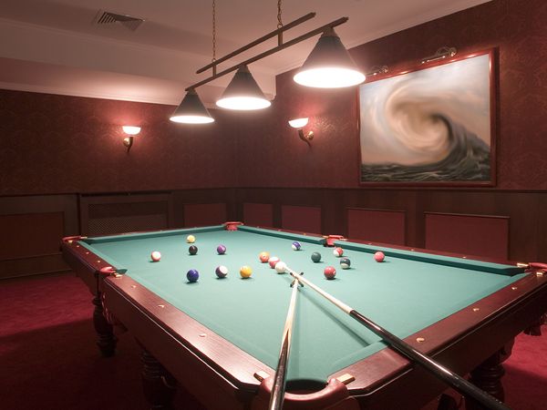 Pool table in recreation room with balls and cues. 