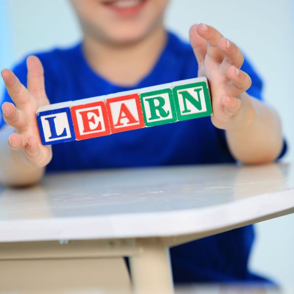 kid holding blocks that spell learn