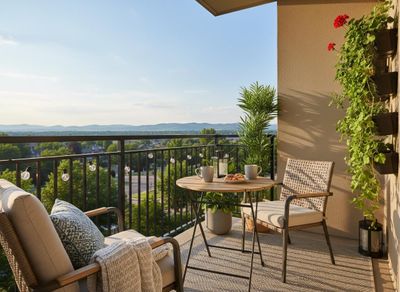A sunny apartment balcony with outdoor furniture, potted plants, and a small table with coffee and pastries, overlooking a vast mountain landscape. Furnished Balcony with Mountain View and Breakfast