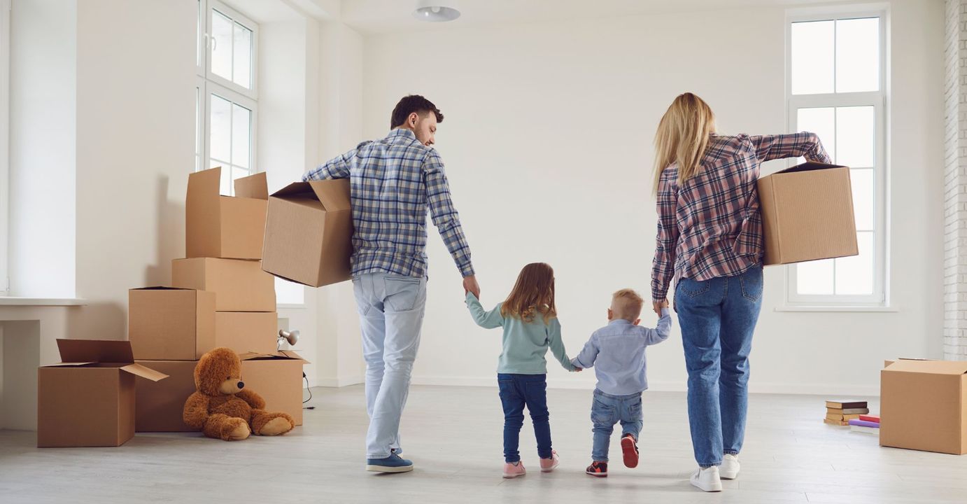 family carrying boxes into their new apartment