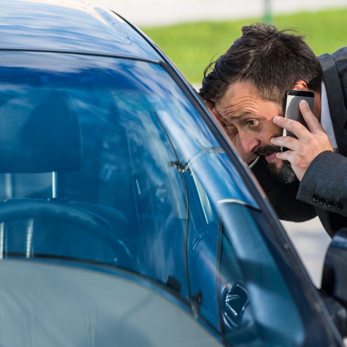 Man on phone looking in car window