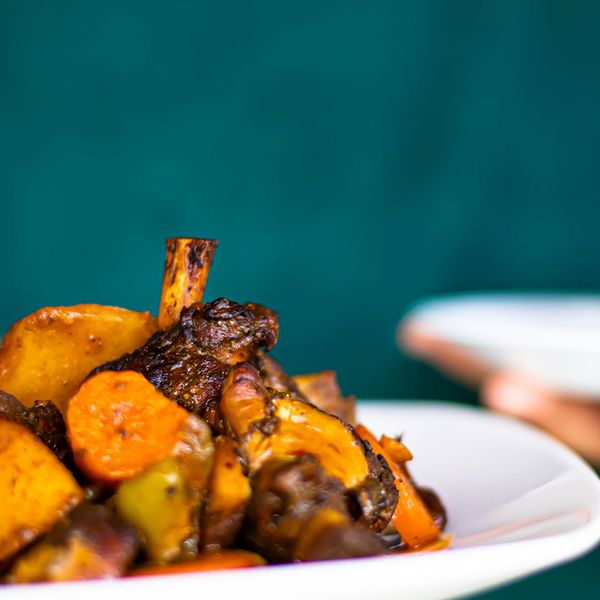 A server bringing out a dish of Jamaican jerk chicken with vegetables.