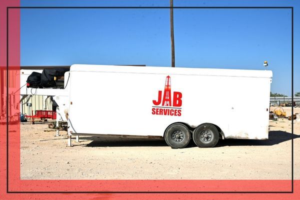 image of a white trailer outside with the logo for JAB Services on the side