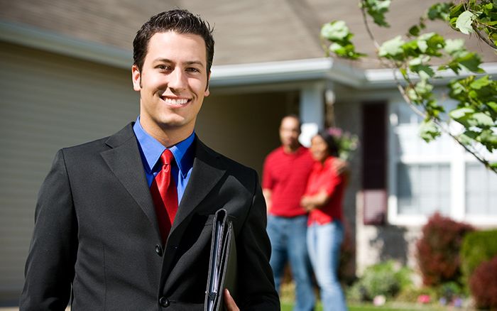 a realtor holding a binder in front of a home