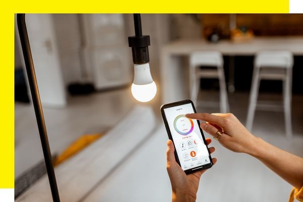 Woman using a smartphone app to adjust a smart LED light bulb.