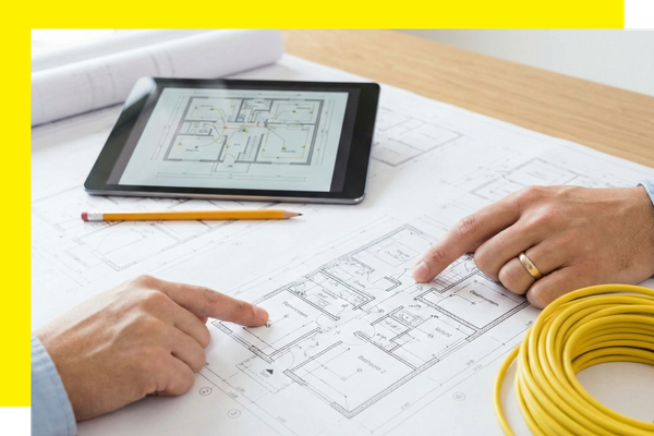 Two people reviewing electrical blueprints and a digital floor plan on a tablet for a new house project.