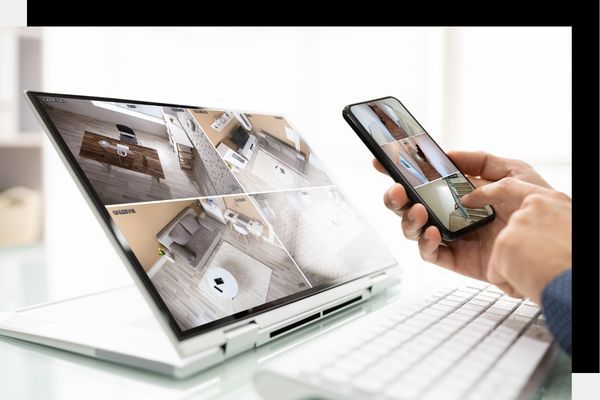 Laptop and smartphone screens displaying grid views of real-time security camera feeds.
