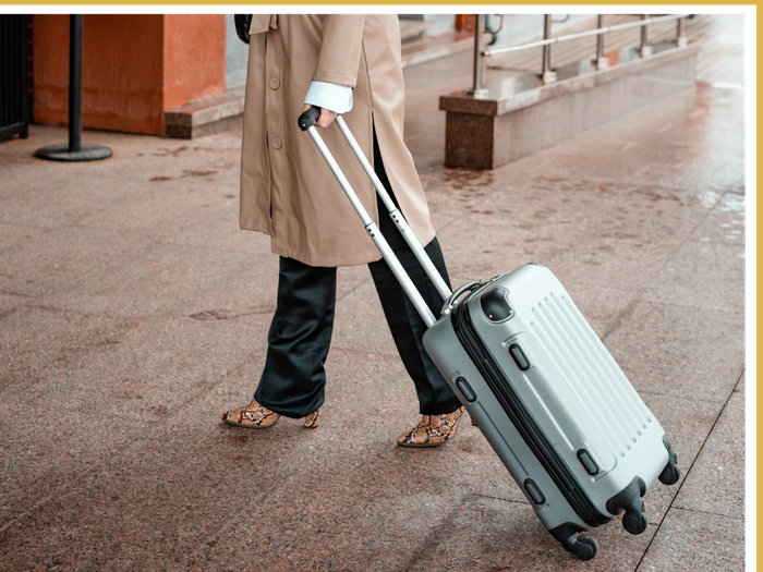 woman rolling suitcase into the airport