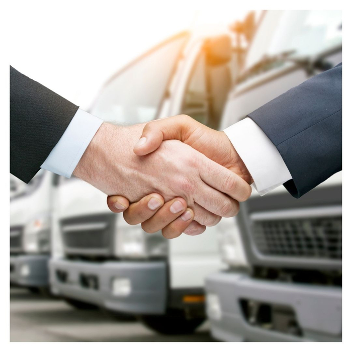 shaking hands in front of vehicles