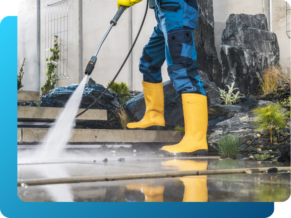 crew member pressure washing residential pavement and steps
