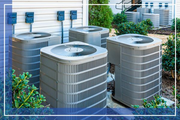 Vertical shot of four apartment air conditioners outside.