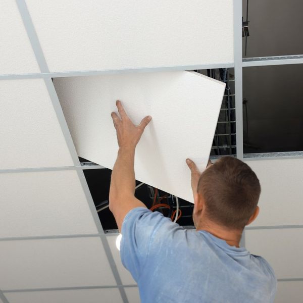 person installing ceiling tiles