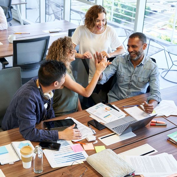 People in an office having a happy conversation and high-fiving. 