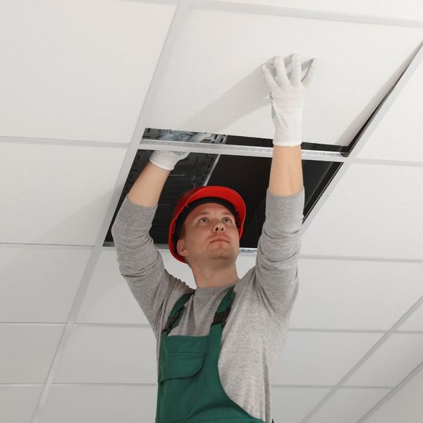 man repairing a suspended ceiling tile