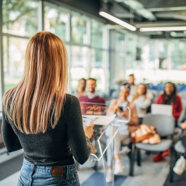 Woman presenting to a room of people. 