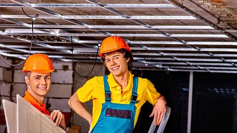 Two men installing a suspended ceiling. 