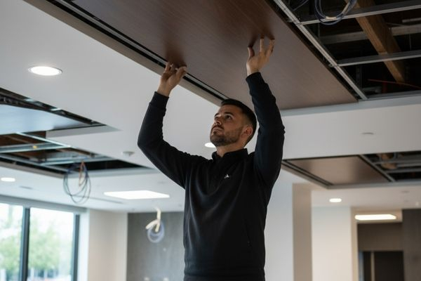 a skilled ceiling contractor from LA Ceilings carefully installing a section of a suspended or custom ceiling