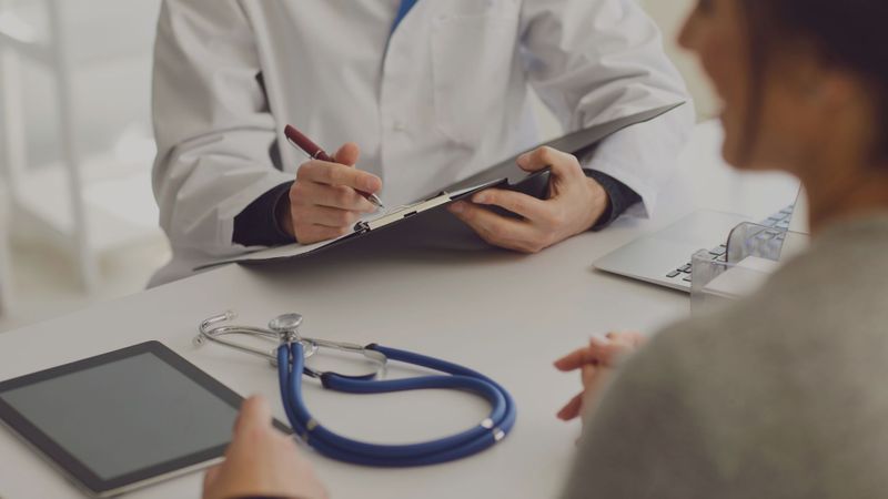 Doctor with patient writing on clipboard 