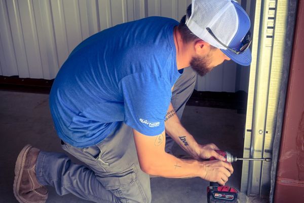 man in hat uses drill to screw in garage door track Roller track repair 1.jpg