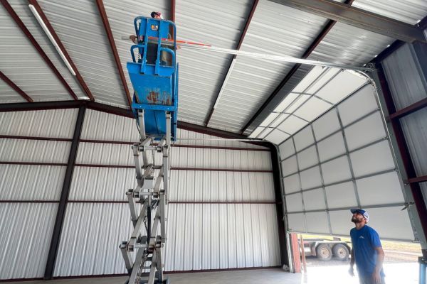 2 men in garage with one on scissor lift installing garage door track Roller track repair 3.jpg