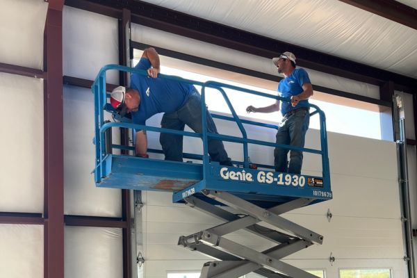 installers on lift putting up garage door panels Panel Replacement 1.jpg