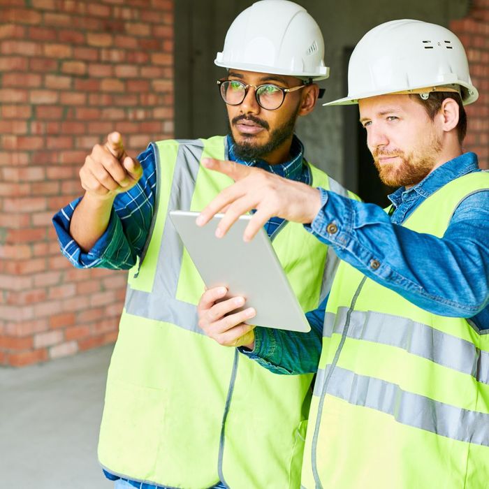 Two construction workers looking at tablet and pointing 