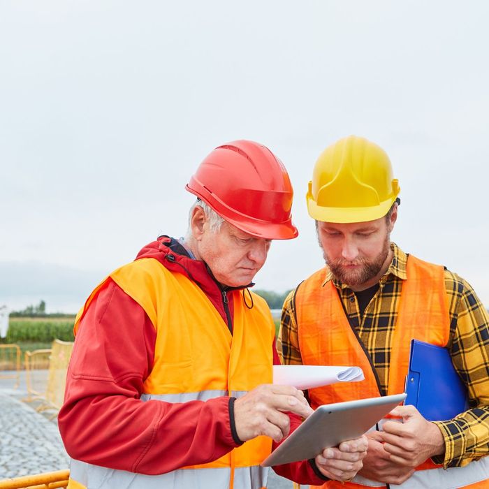Two construction workers typing on tablet