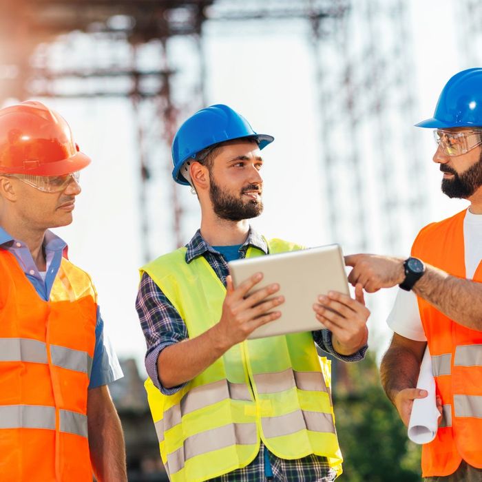 Three men in construction gear looking at tablet