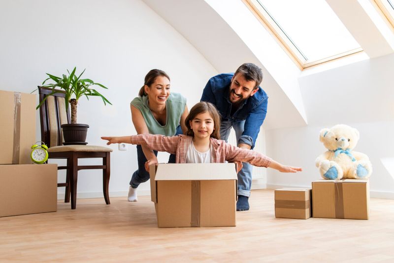couple pushing daughter for ride in moving box