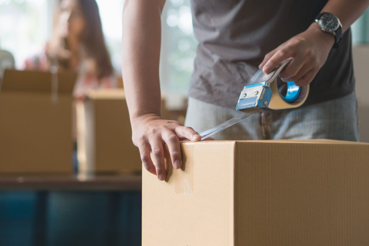 man using packing tape to close box