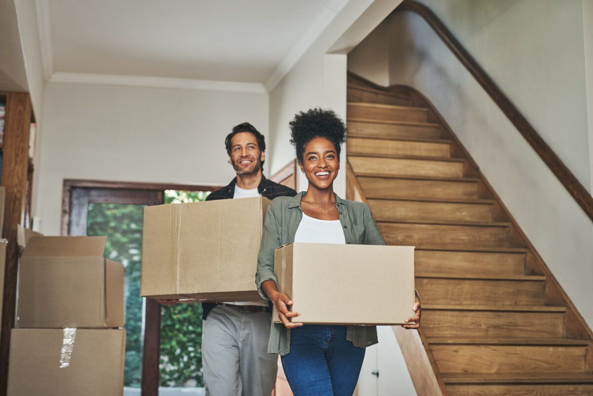 couple carrying boxes into new home