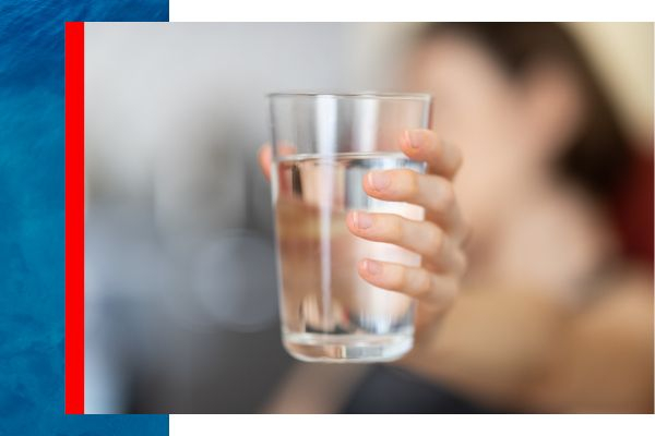 A woman holding out a glass of crystal clear water