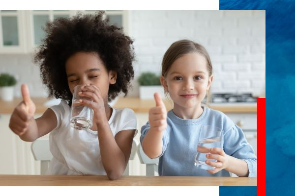 Two young girls drinking water and giving a thumbs-up