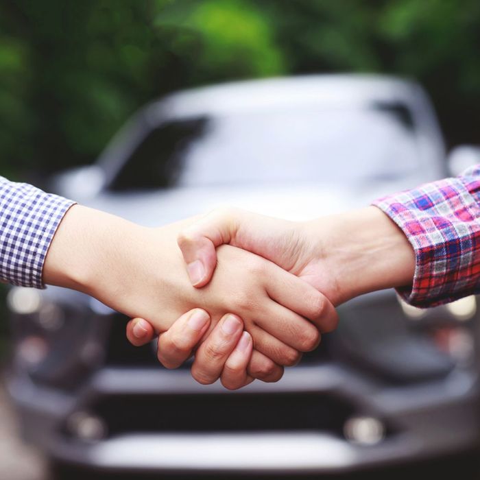 shaking hands in front of car